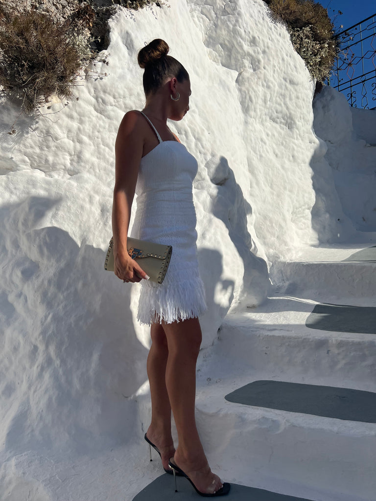  A stylish dress with a square neckline, slim rouleau straps, fringe trim at the hemline, and a mini length. It is fully lined and has a back zip closure."